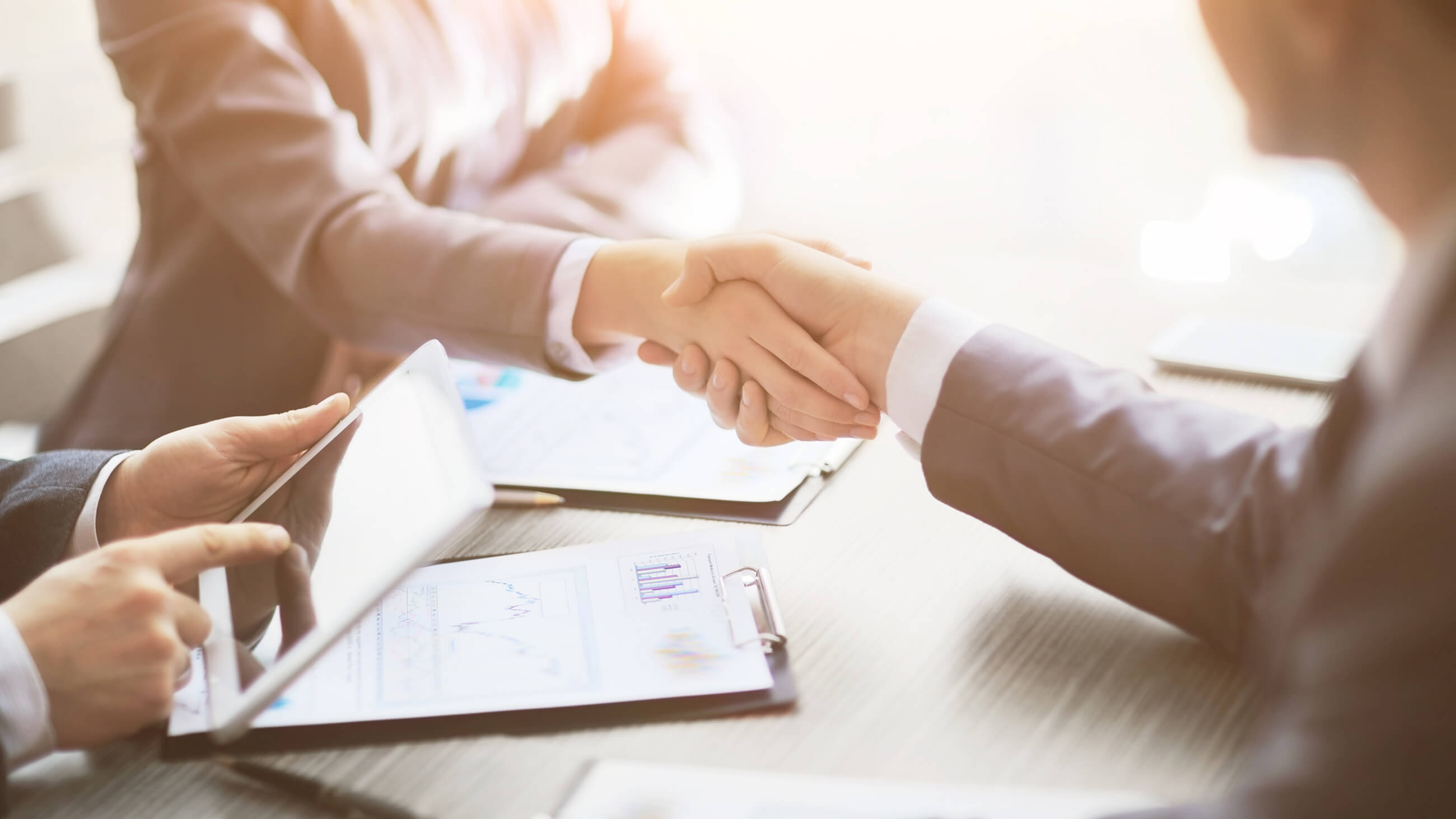 business associates shaking hands over a wooden table