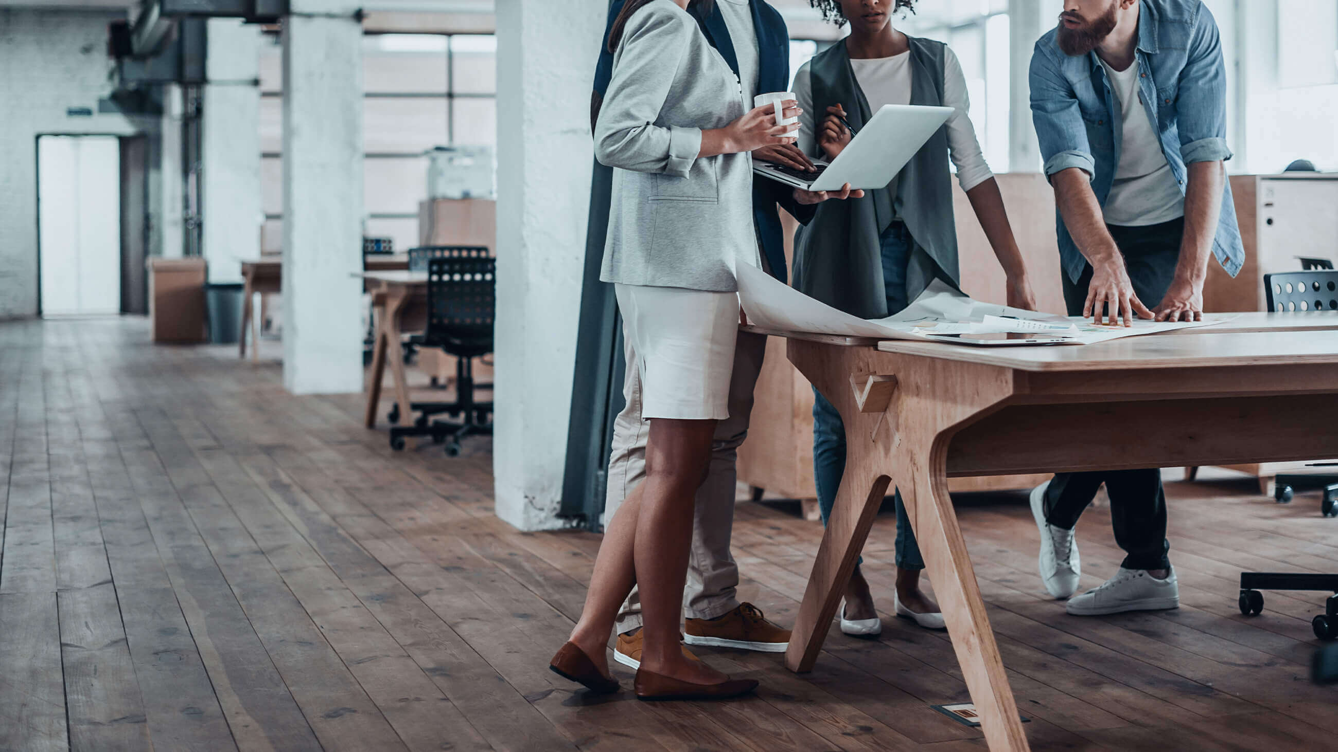 four business associates looking over blueprint in an office setting