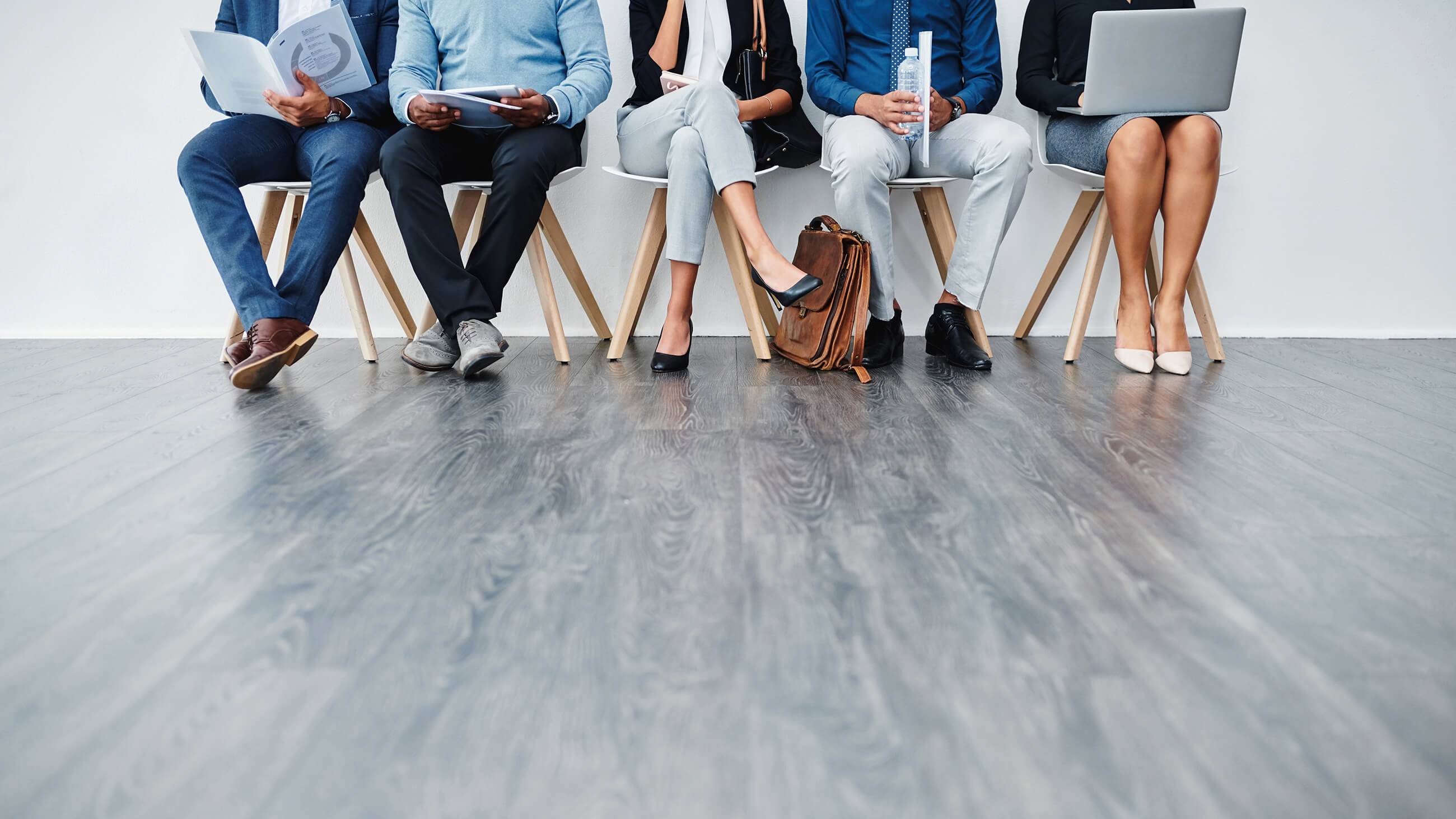 five people in business attire sitting on white chairs